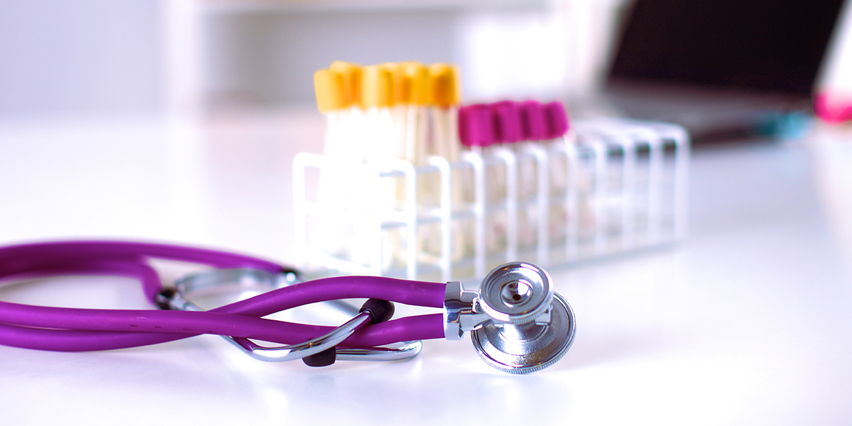 A purple stethoscope and a rack of medical test tubes on a white surface, representing a Fortune 100 healthcare system in a Strategic Benefits Advisors case study on modernizing employee recognition programs.