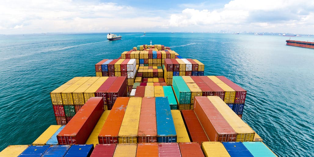 A large cargo ship carrying stacks of colorful shipping containers across the ocean, representing an international transportation client in a Strategic Benefits Advisors case study on identifying $40 million in disability payment errors.
