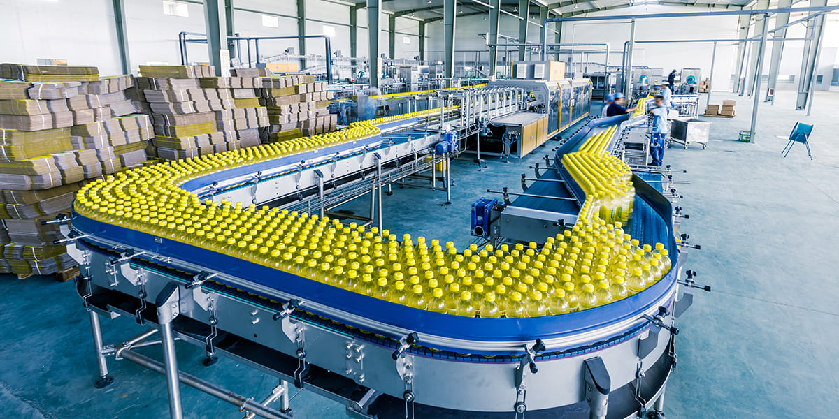 Strategic Benefits Advisors case study regarding a defined benefit pension plan termination strategy for a manufacturing client, featuring a high-angle view of an automated factory conveyor line filled with rows of bright yellow bottles.