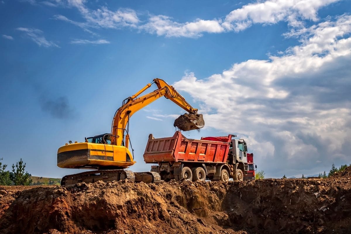 Recovering uncashed benefit checks across international boundaries for a manufacturing client, featuring a yellow excavator loading material into a dump truck.