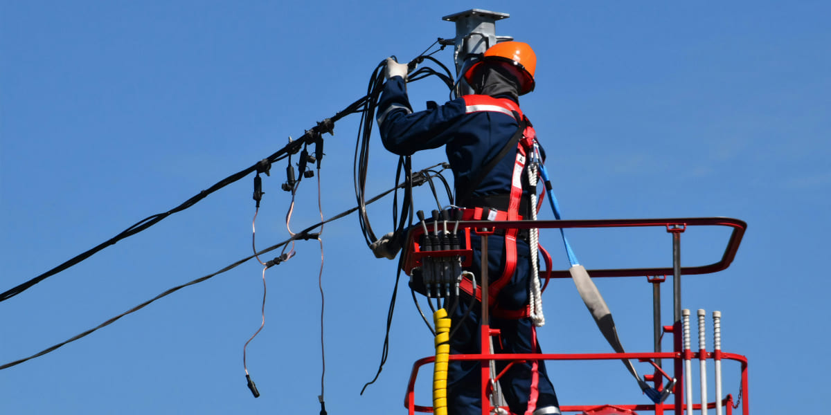 Strategic Benefits Advisors case study regarding an employee recognition vendor search for a regional utility company, depicting a utility technician in an orange hard hat working on overhead wires from a red bucket lift against a clear blue sky.