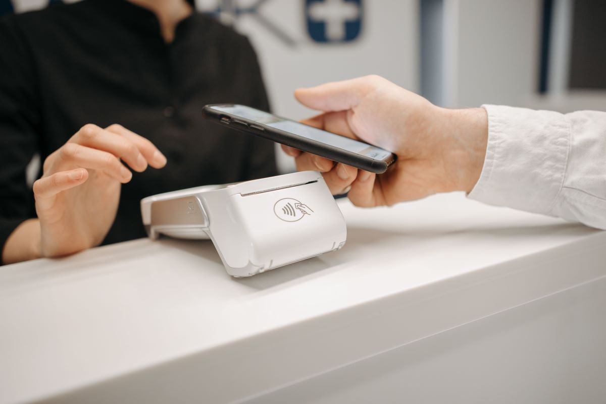 Strategic Benefits Advisors case study regarding redesigning leave administration for a post-merger payment technology company, showing a close-up of a contactless smartphone payment at a terminal.