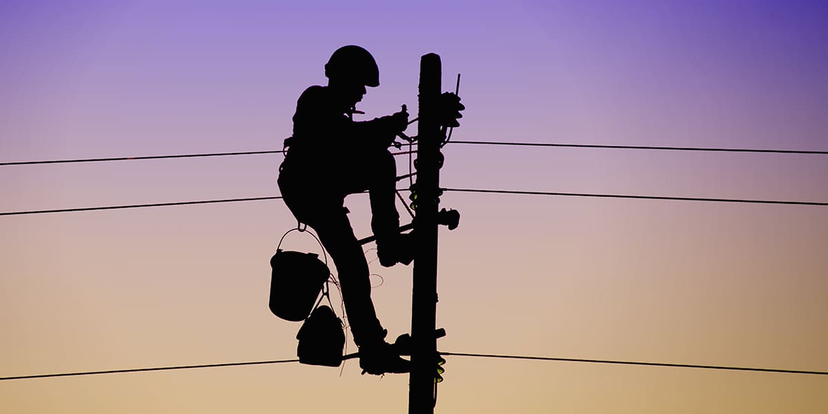 Strategic Benefits Advisors case study regarding auditing pension benefit calculations for an energy services company, showing the silhouette of a utility lineman working on a power pole against a gradient sunset sky.