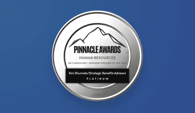 A circular silver Pinnacle Awards badge set against a solid blue background. The top features a mountain peak emblem above text reading "PINNACLE AWARDS," "HUMAN RESOURCES," and "HR CONSULTANT / ADVISORY PARTNER OF THE YEAR". A black banner across the center reads "Kim Shumate/Strategic Benefits Advisors" above "PLATINUM".